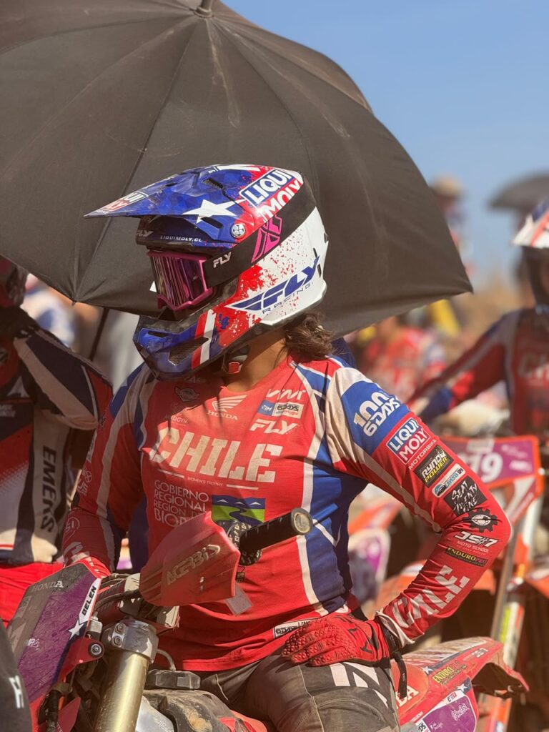 Belén Norambuena espera la largada bajo una sombrilla, con el casco de la bandera chilena